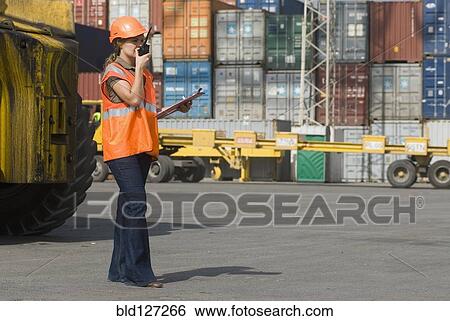 Woman wearing hard hat using walkie-talkie at container terminal View Large Photo Image Stock Photograph - Woman wearing hard hat using walkie-talkie at container terminal. Fotosearch