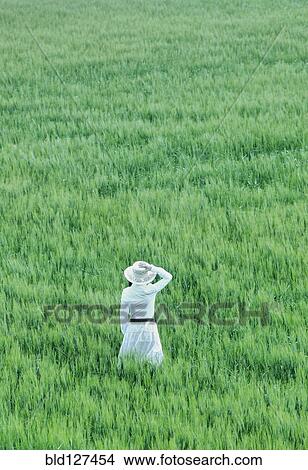 Woman wearing hat standing in field rear view View Large Photo Image Picture - Woman wearing hat standing in field rear view. Fotosearch