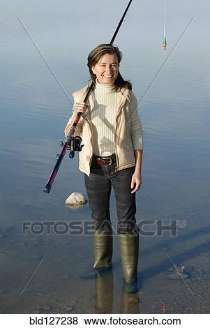 Woman with fishing rod standing in lake portrait elevated view View Large Photo Image Stock Photo - Woman with fishing rod standing in lake portrait elevated view. Fotosearch
