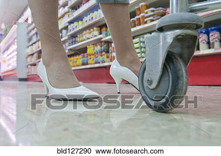 Stock Image - woman's feet and shopping trolley. Fotosearch