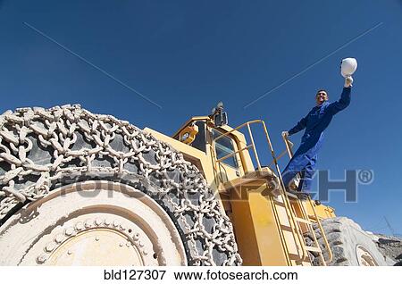 worker waving hard hat standing on mining machine View Large Photo Image Stock Photo - worker waving hard hat standing on mining machine. Fotosearch