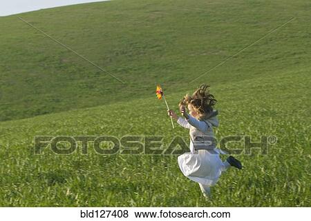 young girl with wind wheel running in green fields View Large Photo Image Stock Photo - young girl with wind wheel running in green fields. Fotosearch