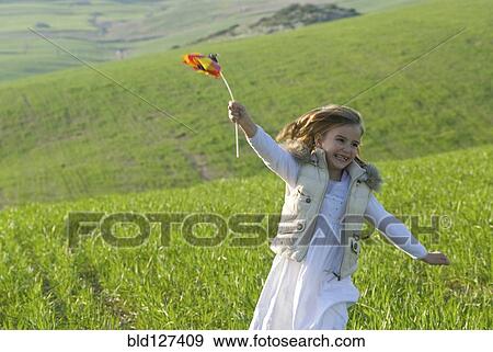 young girl with wind wheel running in green fields View Large Photo Image Stock Photo - young girl with wind wheel running in green fields. Fotosearch