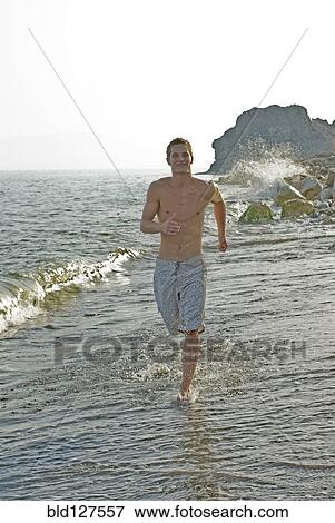 Stock Photo - young man running in surf. Fotosearch