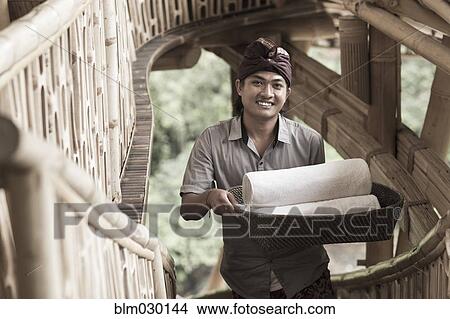 Picture - Balinese man carrying rolled towels in hotel, Ubud, Bali, Indonesia. Fotosearch