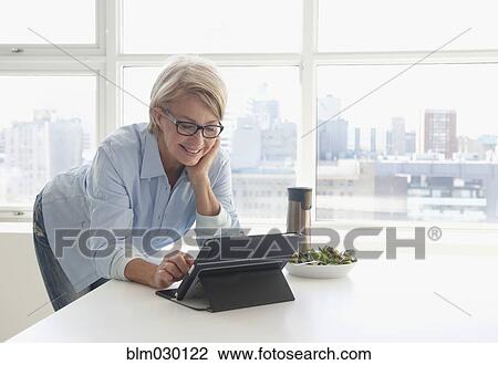 Stock Image - Caucasian woman using digital tablet at lunch. Fotosearch