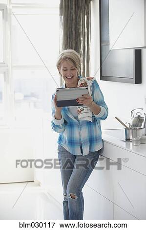 Caucasian woman using digital tablet in kitchen View Large Photo Image Stock Photo - Caucasian woman using digital tablet in kitchen. Fotosearch
