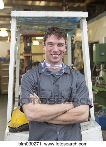 Stock Image - Caucasian worker smiling in warehouse. Fotosearch