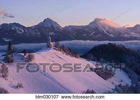 Stock Photo - Church on hilltop in snowy landscape, Kropa, Gorenjska, Slovenia. Fotosearch