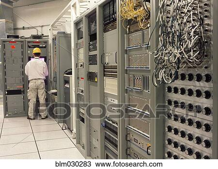 Stock Image - Computer programmer working in server room. Fotosearch