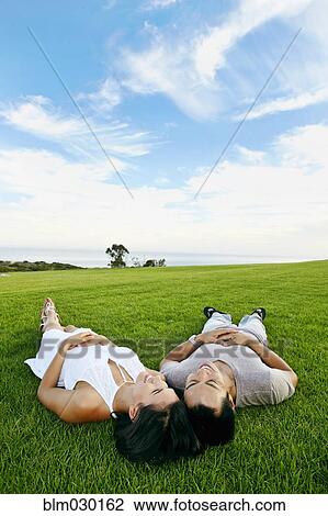 Stock Image - Couple laying in grass in rural landscape. Fotosearch