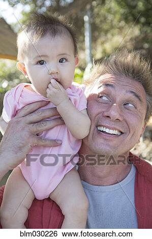 Stock Photograph - Father playing with baby girl outdoors. Fotosearch