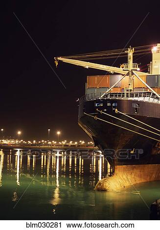 Stock Image - Illuminated crane and container ship at night, Port of Los Angeles, California, United States. Fotosearch