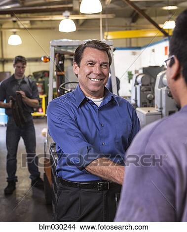 Picture - Manager and worker shaking hands in warehouse. Fotosearch