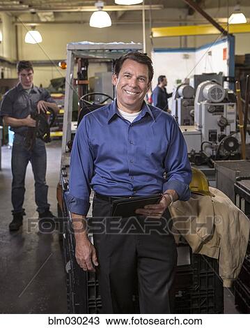 Stock Image - Manager using digital tablet in warehouse. Fotosearch