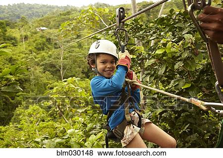 Mixed race boy zip lining View Large Photo Image Stock Photo - Mixed race boy zip lining. Fotosearch