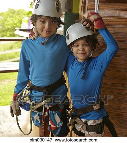 Stock Photo - Mixed race boys preparing to zip line. Fotosearch