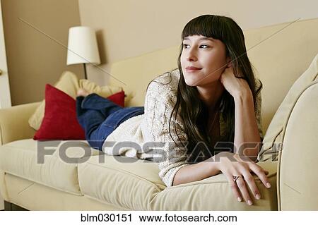 Stock Image - Mixed race woman laying on sofa. Fotosearch
