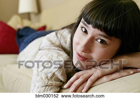 Stock Image - Mixed race woman laying on sofa. Fotosearch