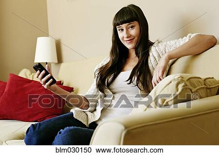 Mixed race woman using cell phone on sofa View Large Photo Image Stock Image - Mixed race woman using cell phone on sofa. Fotosearch