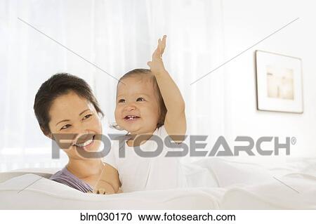 Stock Image - Mother and baby girl in living room. Fotosearch
