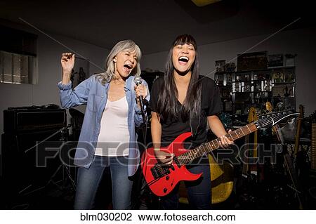 Stock Image - Mother and daughter playing music guitar in basement. Fotosearch