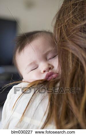 Stock Photo - Mother holding sleeping baby girl. Fotosearch