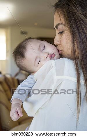 Stock Photo - Mother kissing sleeping baby girl. Fotosearch