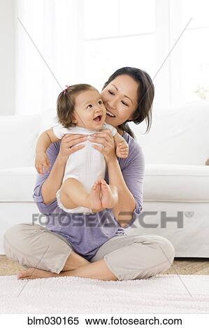 Mother playing with baby girl in living room View Large Photo Image Stock Photography - Mother playing with baby girl in living room. Fotosearch