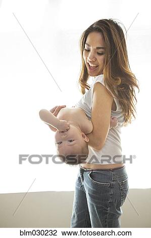 Stock Image - Mother playing with baby girl. Fotosearch
