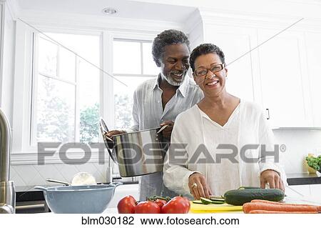 Stock Image - Senior couple cooking in kitchen. Fotosearch