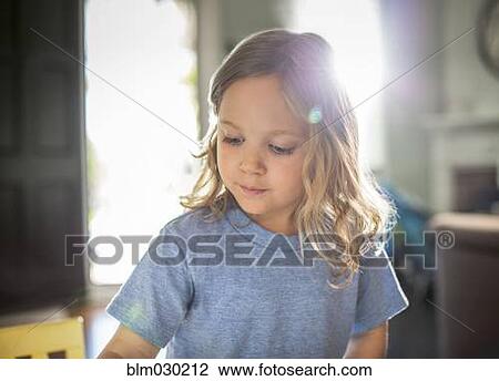 Stock Image - Sun shining behind girl in living room. Fotosearch