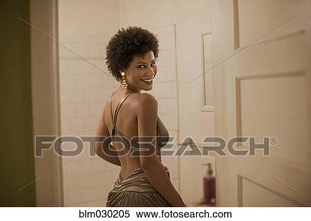 Stock Photography - Woman in dress smiling in bathroom. Fotosearch