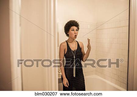 Stock Photo - Woman making a face in bathroom mirror. Fotosearch