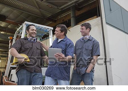 Workers using digital tablet at warehouse loading dock View Large Photo Image Stock Photo - Workers using digital tablet at warehouse loading dock. Fotosearch
