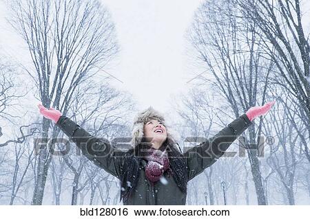 Stock Photograph - Asian woman cheering in snowy park. Fotosearch