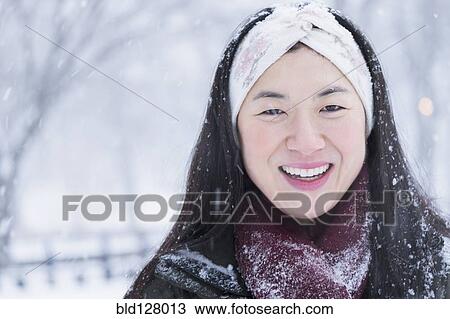 Stock Image - Asian woman smiling in snow. Fotosearch