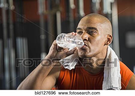 Stock Photograph - Black man drinking water in gym. Fotosearch