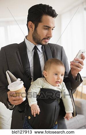 Stock Image - Businessman carrying baby and cell phone. Fotosearch