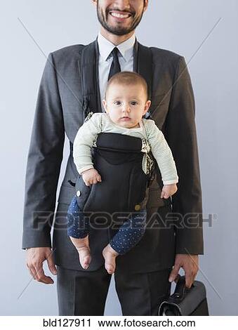 Stock Image - Businessman carrying baby in carrier. Fotosearch