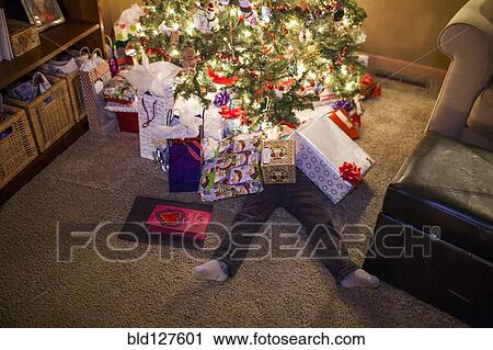 Stock Image - Caucasian boy buried in Christmas gifts. Fotosearch