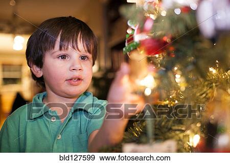 Stock Photo - Caucasian boy decorating Christmas tree. Fotosearch