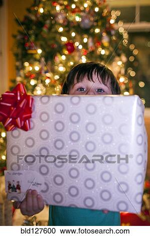 Stock Image - Caucasian boy holding Christmas gift. Fotosearch