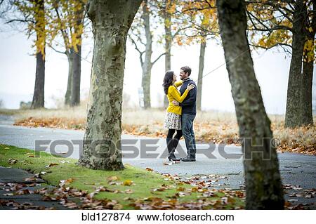 Caucasian couple hugging in park View Large Photo Image Picture - Caucasian couple hugging in park. Fotosearch