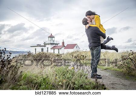 Stock Photography - Caucasian couple hugging on beach path. Fotosearch
