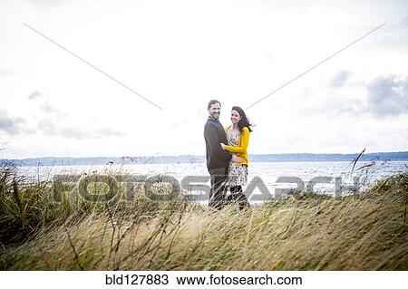 Caucasian couple hugging on grassy beach View Large Photo Image Stock Image - Caucasian couple hugging on grassy beach. Fotosearch