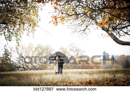 Stock Photo - Caucasian couple kissing under umbrellas. Fotosearch