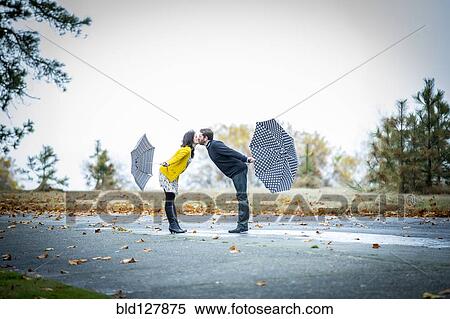 Caucasian couple with umbrellas kissing outdoors View Large Photo Image Stock Photography - Caucasian couple with umbrellas kissing outdoors. Fotosearch