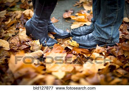 Stock Photo - Caucasian couple's feet in autumn leaves. Fotosearch