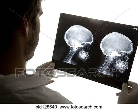 Stock Image - Caucasian doctor examining x-rays in hospital. Fotosearch